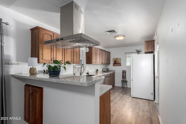 kitchen featuring dishwasher, sink, white refrigerator, island exhaust hood, and light wood-type flooring