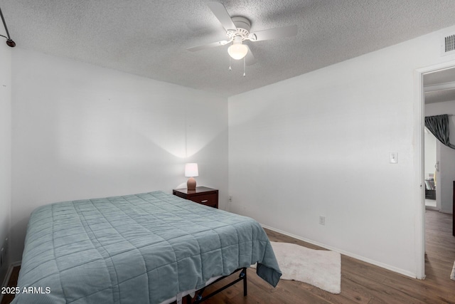 bedroom with ceiling fan, hardwood / wood-style flooring, and a textured ceiling