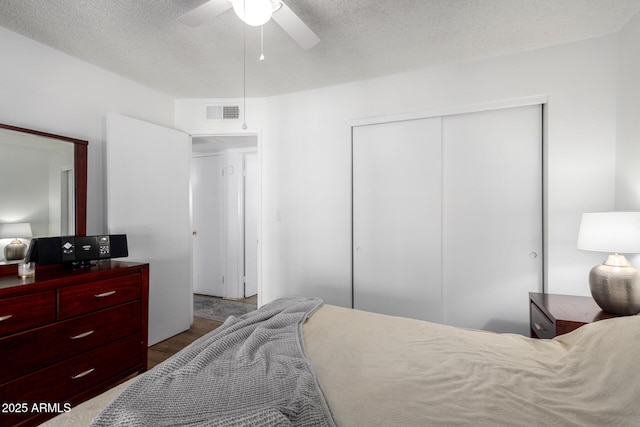 bedroom with ceiling fan, wood-type flooring, a closet, and a textured ceiling