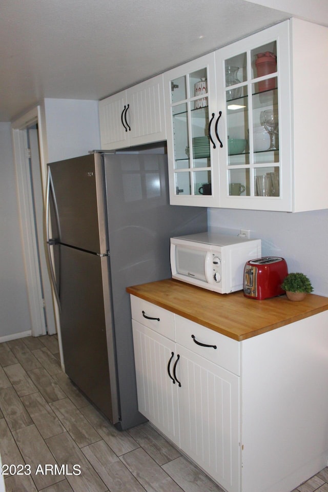 7120 E Wilshire Dr Unit 10, Scottsdale, AZ 85257 - kitchen with white microwave, wood counters, light wood finished floors, white cabinets, and glass insert cabinets