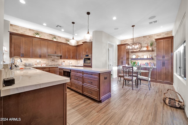 kitchen with sink, oven, hanging light fixtures, and light hardwood / wood-style flooring