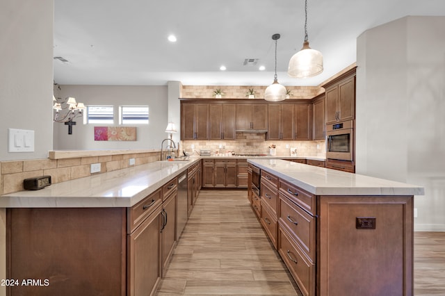 kitchen featuring kitchen peninsula, light stone counters, sink, pendant lighting, and light hardwood / wood-style floors