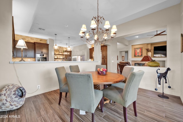 dining room featuring ceiling fan with notable chandelier and light hardwood / wood-style floors