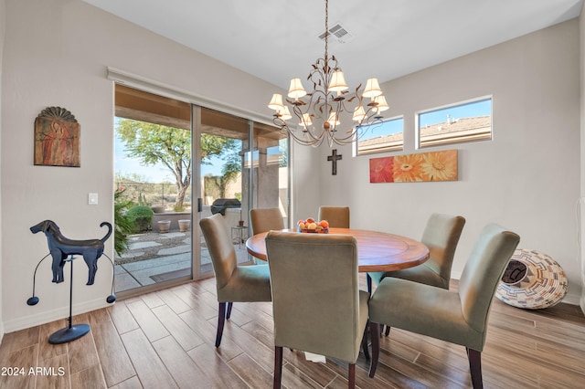 dining space featuring hardwood / wood-style floors, a healthy amount of sunlight, and an inviting chandelier