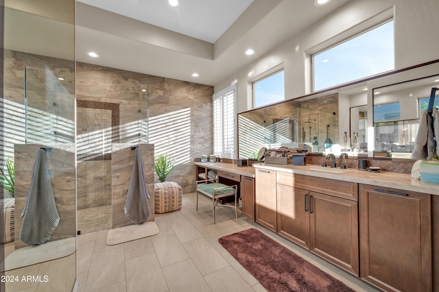 bathroom with a tile shower, tile patterned floors, vanity, and tile walls