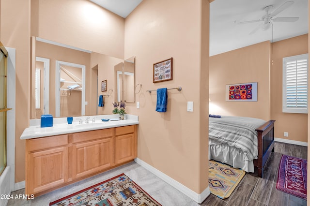 bathroom with combined bath / shower with glass door, wood-type flooring, vanity, and ceiling fan