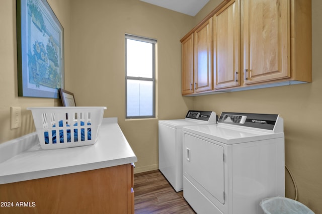 washroom with washer and clothes dryer, cabinets, and hardwood / wood-style flooring