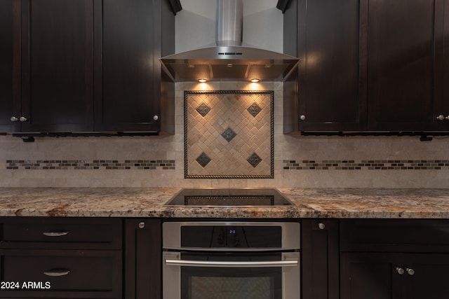 kitchen with backsplash, black electric cooktop, oven, light stone countertops, and range hood