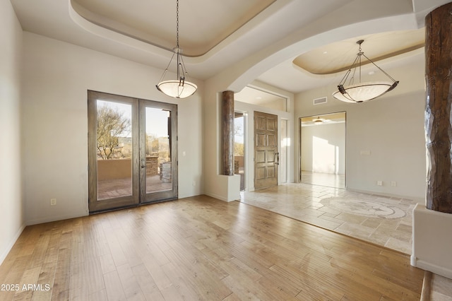 interior space with french doors, a tray ceiling, ceiling fan, and wood-type flooring