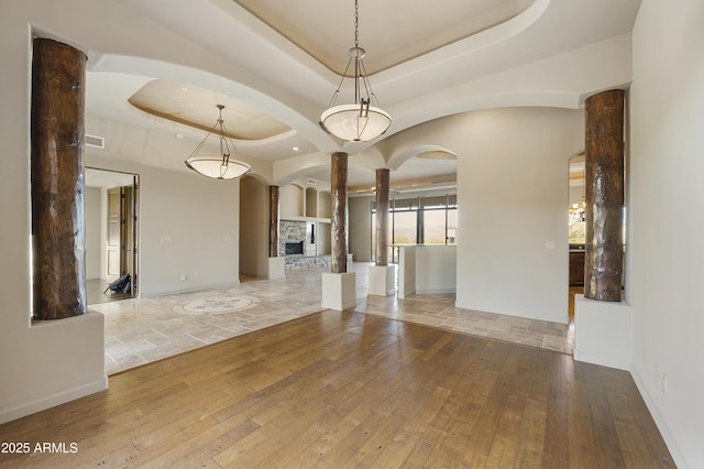 unfurnished room featuring a tray ceiling, a fireplace, and hardwood / wood-style floors