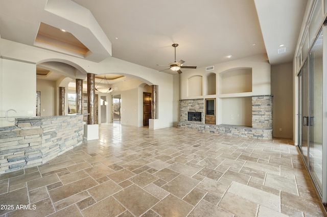 unfurnished living room featuring ceiling fan and a fireplace