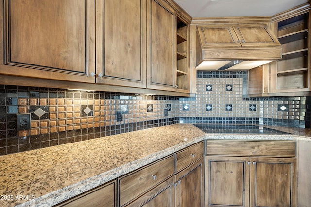 kitchen featuring black electric stovetop, premium range hood, and backsplash