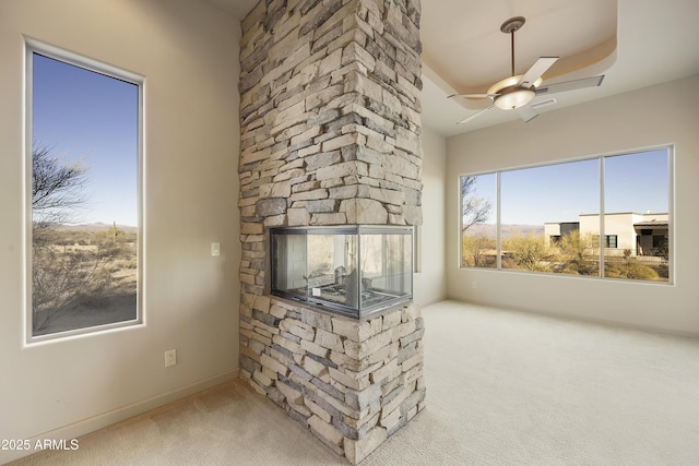 living room featuring ceiling fan, a stone fireplace, and carpet floors