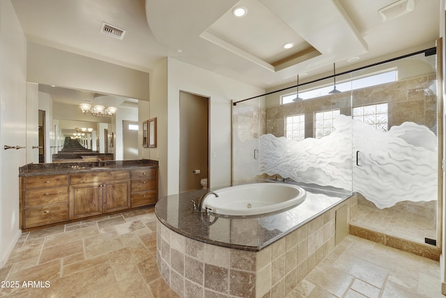 bathroom with plus walk in shower, vanity, a tray ceiling, and a chandelier