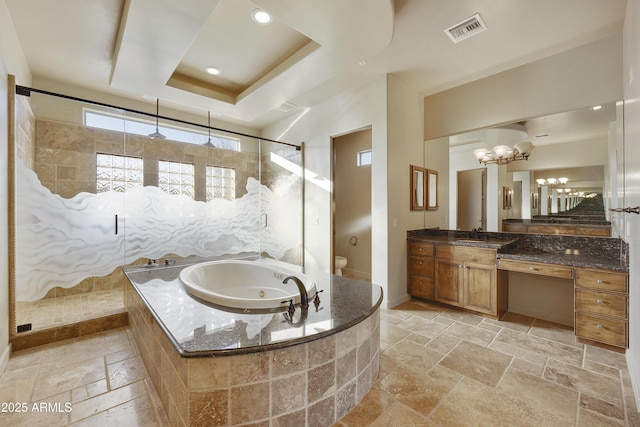 full bathroom with a chandelier, toilet, a tray ceiling, vanity, and shower with separate bathtub