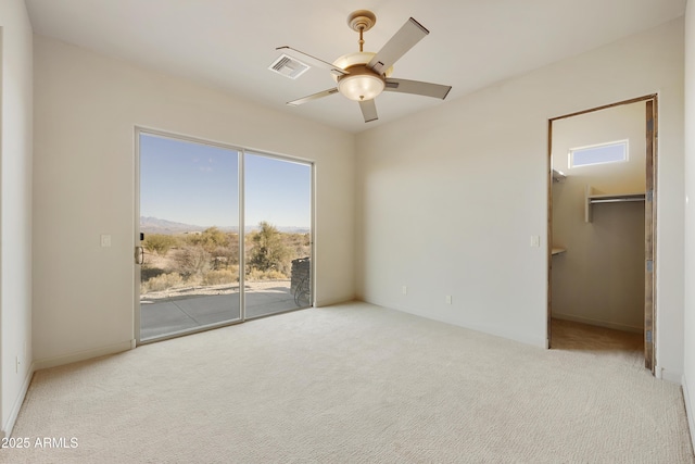 unfurnished bedroom with access to exterior, a spacious closet, ceiling fan, and light carpet