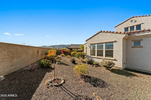 20701 W Minnezona Ave, Buckeye, AZ 85396 - view of side of home with a tiled roof, stucco siding, a mountain view, and fence