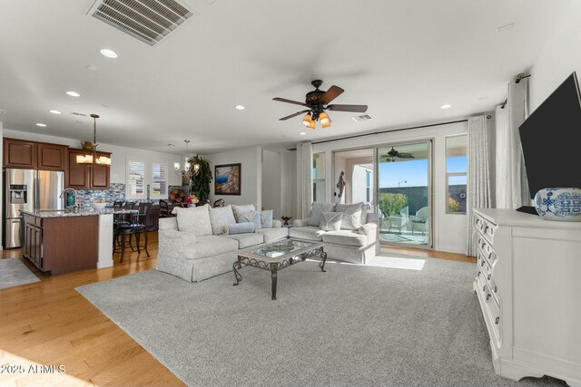 20701 W Minnezona Ave, Buckeye, AZ 85396 - living area featuring recessed lighting, visible vents, light wood-style flooring, and ceiling fan with notable chandelier