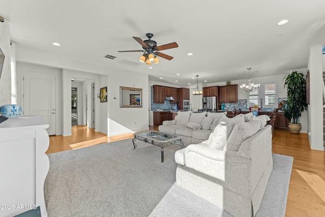 20701 W Minnezona Ave, Buckeye, AZ 85396 - living area with recessed lighting, light wood-type flooring, visible vents, and ceiling fan with notable chandelier