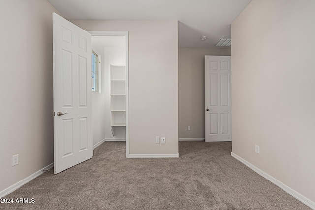 unfurnished bedroom with light carpet and a spacious closet