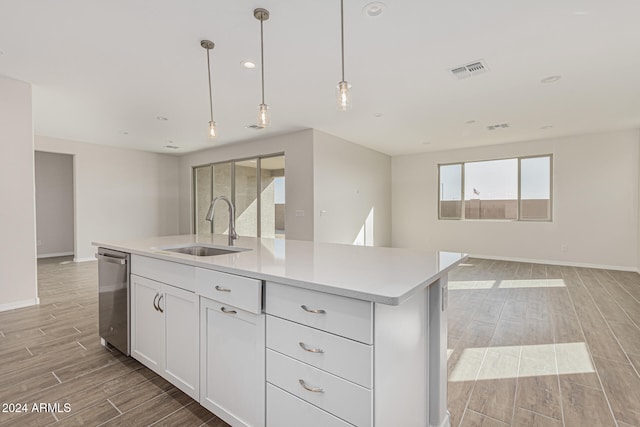 kitchen featuring a kitchen island with sink, sink, stainless steel dishwasher, white cabinets, and light hardwood / wood-style floors