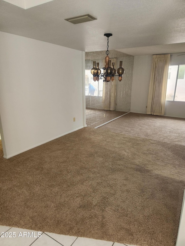 unfurnished dining area featuring visible vents, carpet flooring, a wealth of natural light, and an inviting chandelier