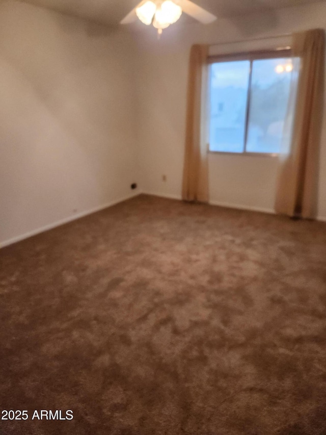 empty room with a ceiling fan and dark colored carpet