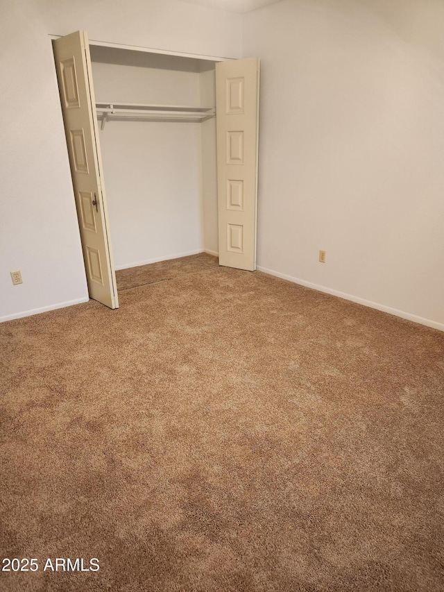 unfurnished bedroom featuring carpet, a closet, and baseboards