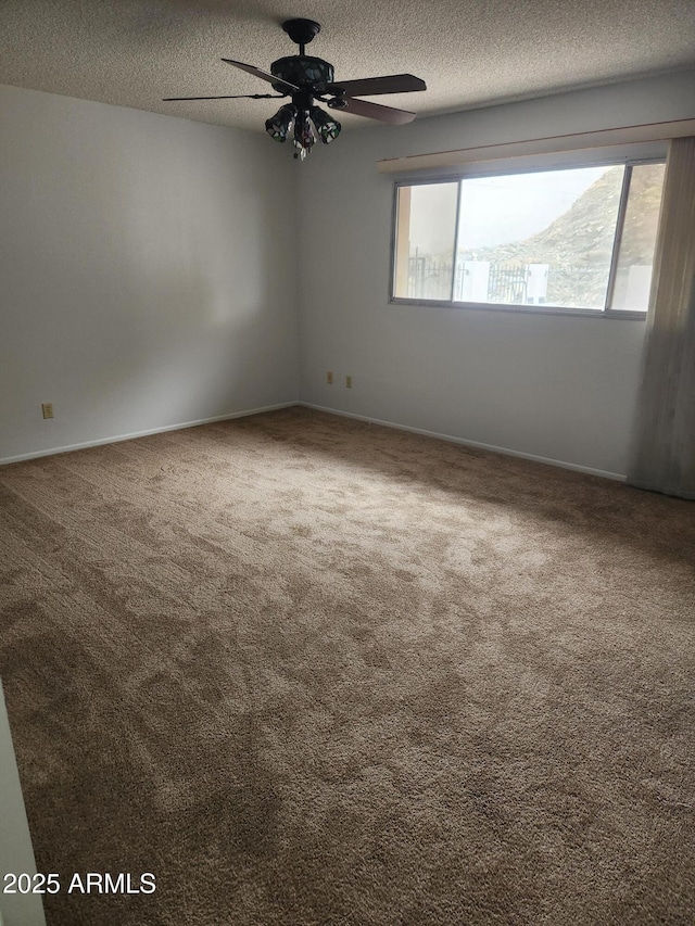 spare room featuring carpet, baseboards, ceiling fan, and a textured ceiling