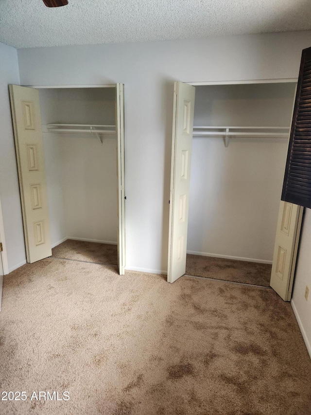 unfurnished bedroom with carpet floors, a textured ceiling, and baseboards