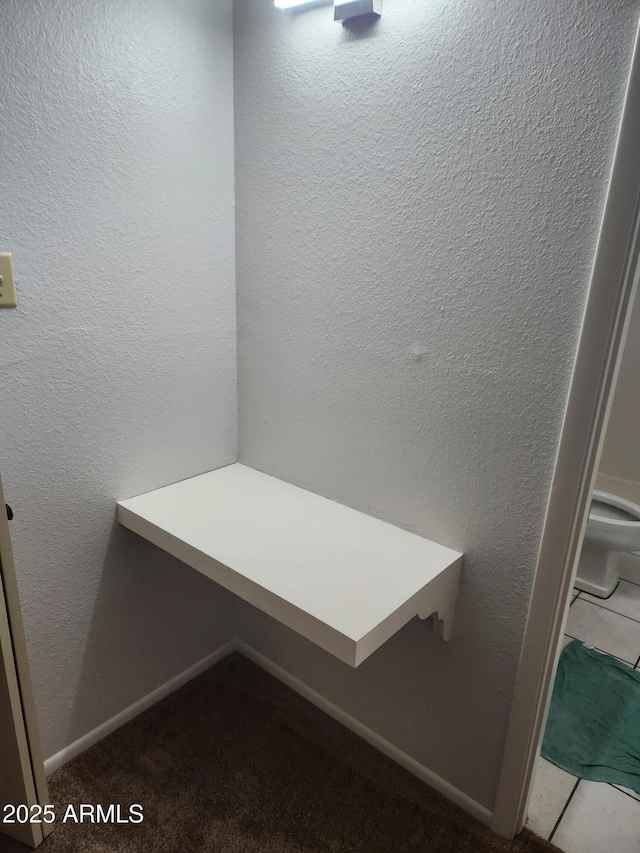 interior space with carpet, a textured wall, and baseboards