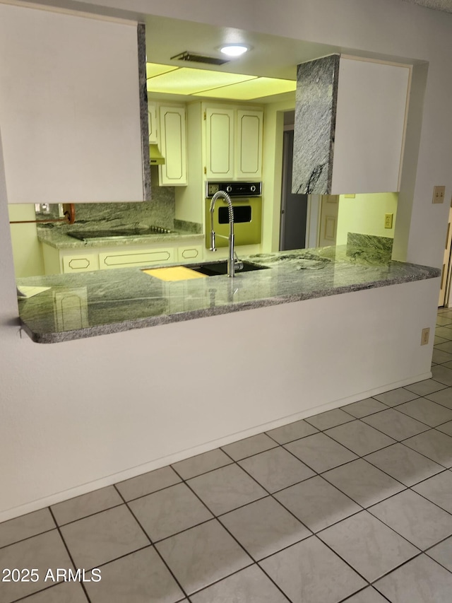 kitchen with oven, a sink, tile patterned flooring, black electric cooktop, and backsplash