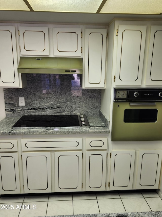 kitchen with tasteful backsplash, oven, black electric stovetop, and light tile patterned floors