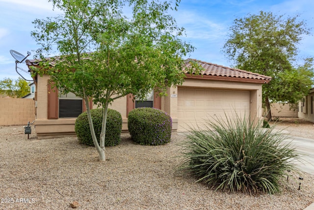 view of front of home featuring stucco siding, a tiled roof, fence, and an attached garage
