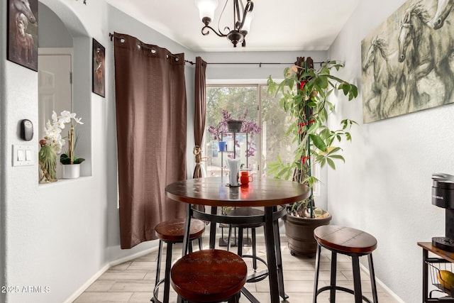 dining room featuring baseboards, light wood-type flooring, and an inviting chandelier