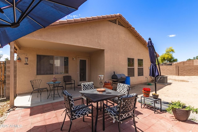 rear view of house with a patio, stucco siding, and fence