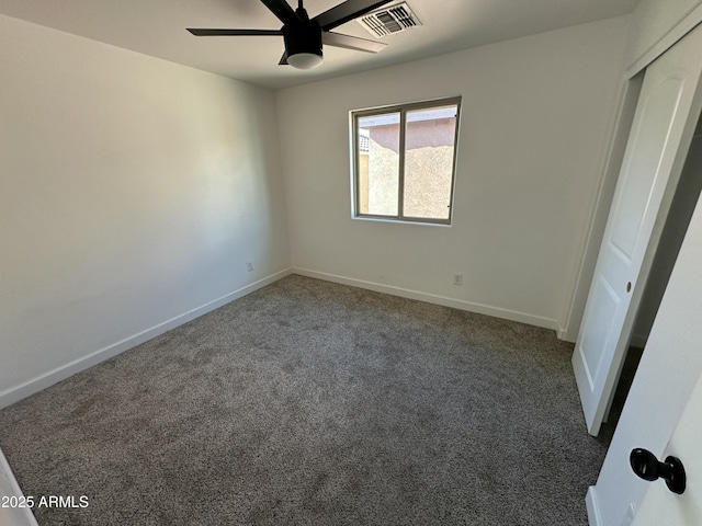 spare room with ceiling fan and dark colored carpet