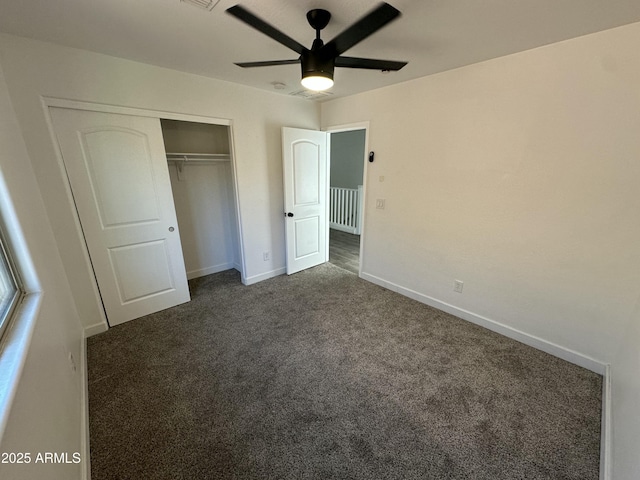 unfurnished bedroom with dark carpet, ceiling fan, and a closet