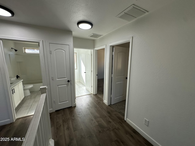 hallway featuring a textured ceiling and dark hardwood / wood-style flooring