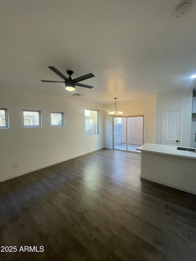 empty room with ceiling fan with notable chandelier and dark hardwood / wood-style floors