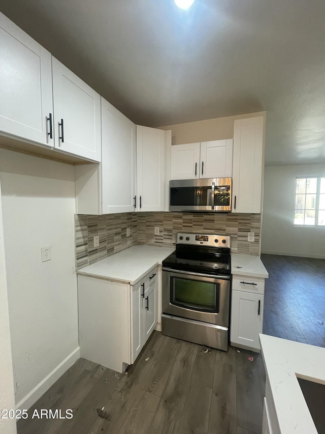 kitchen with white cabinets, dark wood-type flooring, backsplash, and appliances with stainless steel finishes