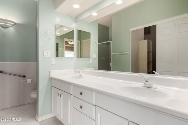 bathroom featuring tile patterned flooring, toilet, a stall shower, and a sink