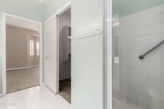 full bathroom with tile patterned flooring, tiled shower, and baseboards