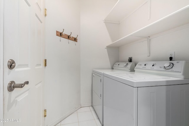 clothes washing area featuring light tile patterned floors, laundry area, baseboards, and separate washer and dryer