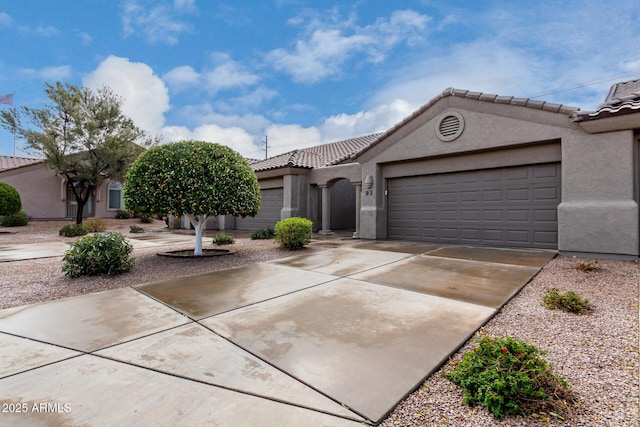 view of front of home with concrete driveway, an attached garage, a tile roof, and stucco siding