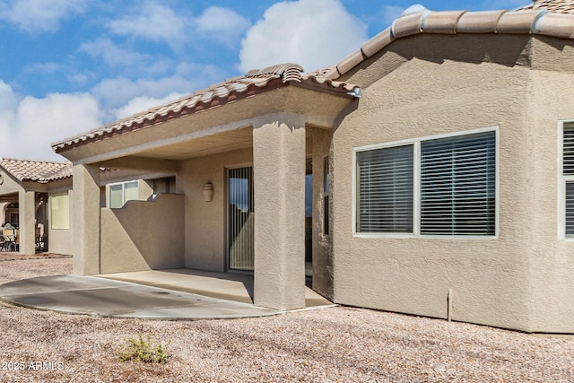 rear view of house featuring a patio area and stucco siding