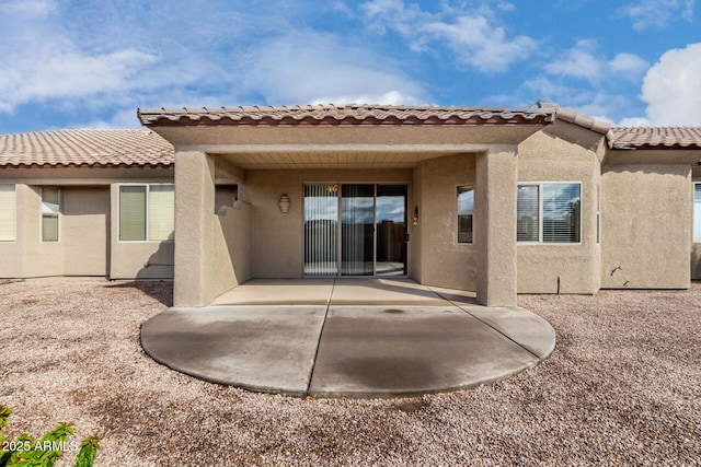 rear view of property featuring a patio area, stucco siding, and a tile roof