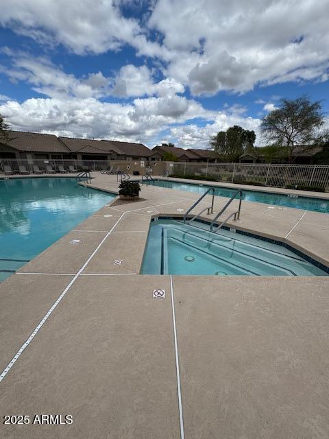 community pool with a patio area and fence