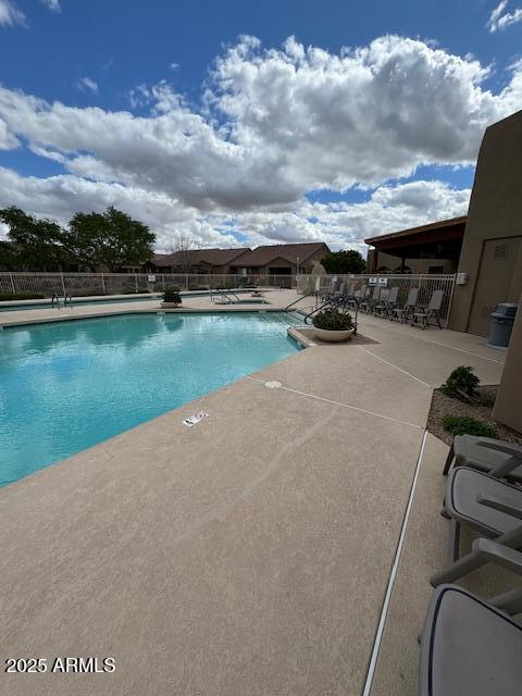 community pool with fence and a patio area