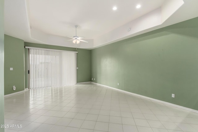 spare room with a tray ceiling, recessed lighting, baseboards, and ceiling fan